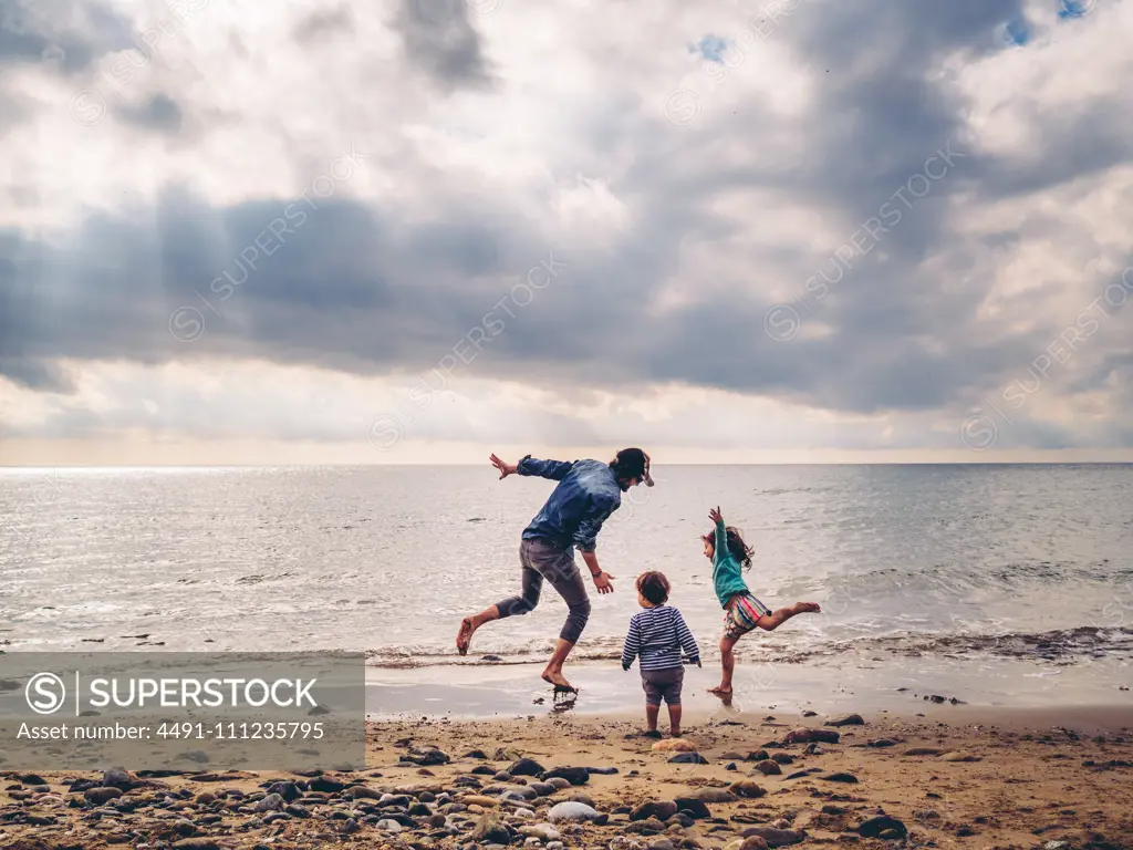 casual father playing with her children by the seashore