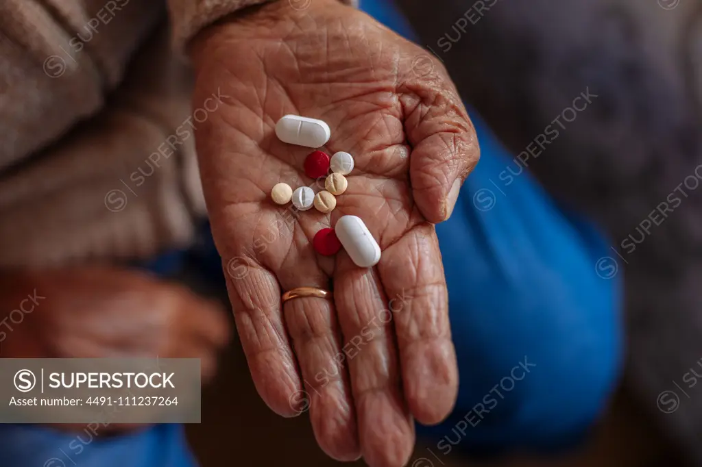 Detail of pills on the hand of an old man