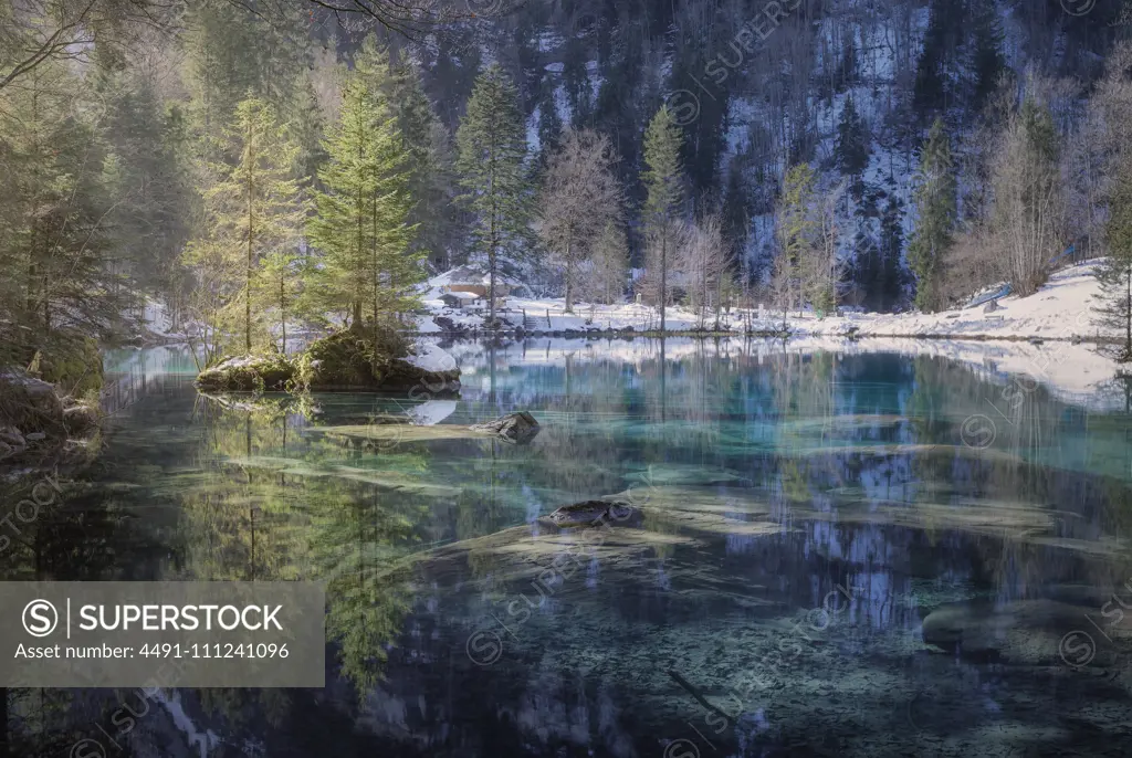 Landscape of peaceful azure lake with snowy shore in mountains of Switzerland