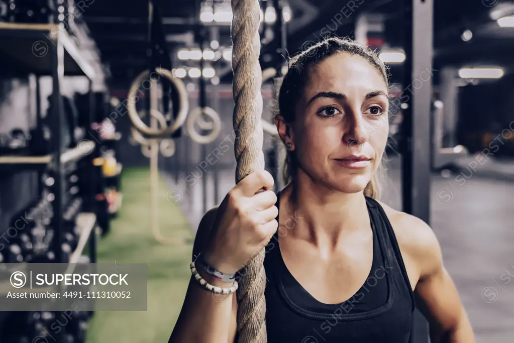 muscular woman with rope and looking way on gym 