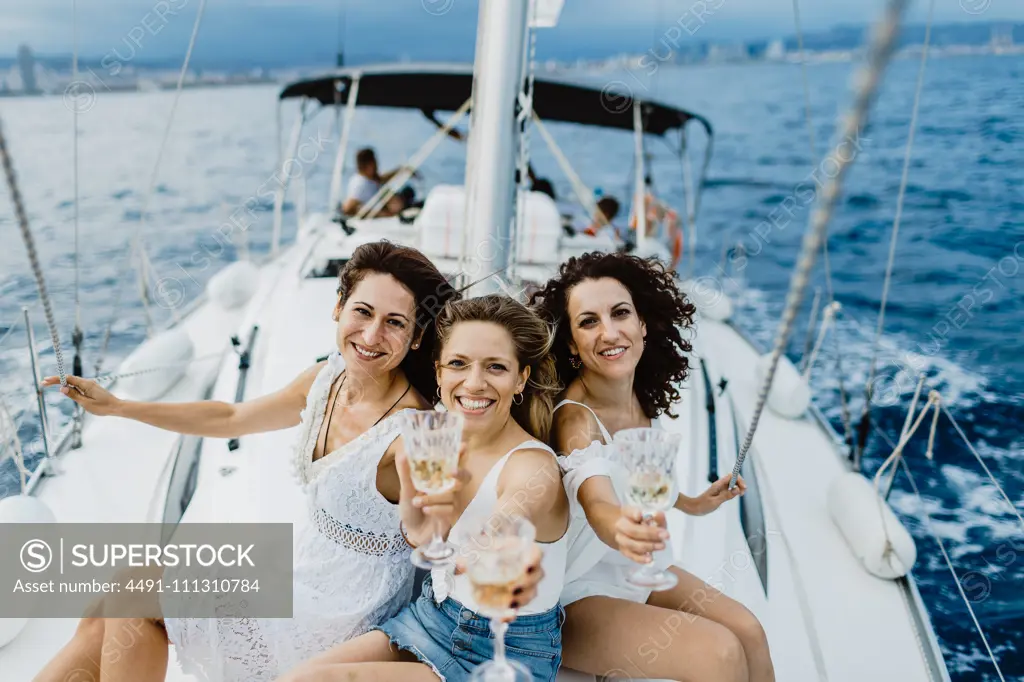 Cheerful friend with wine having fun on yacht 