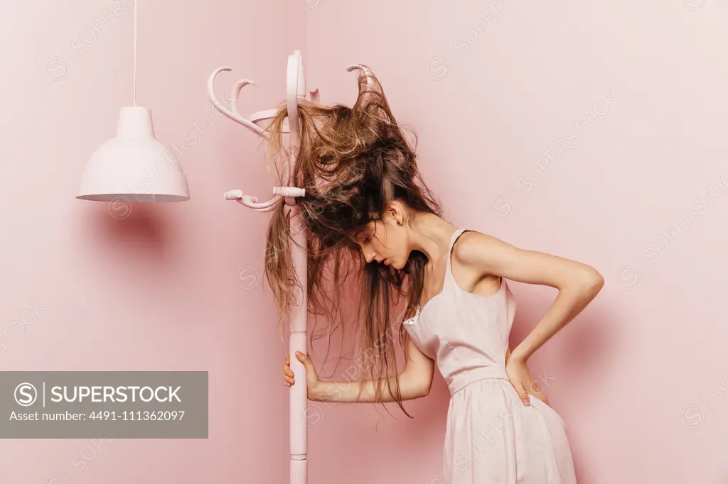 Front view of a teenage girl with tangled hairs on pink background