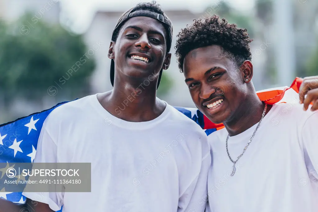 African American men holding American flag on shoulder and looking away