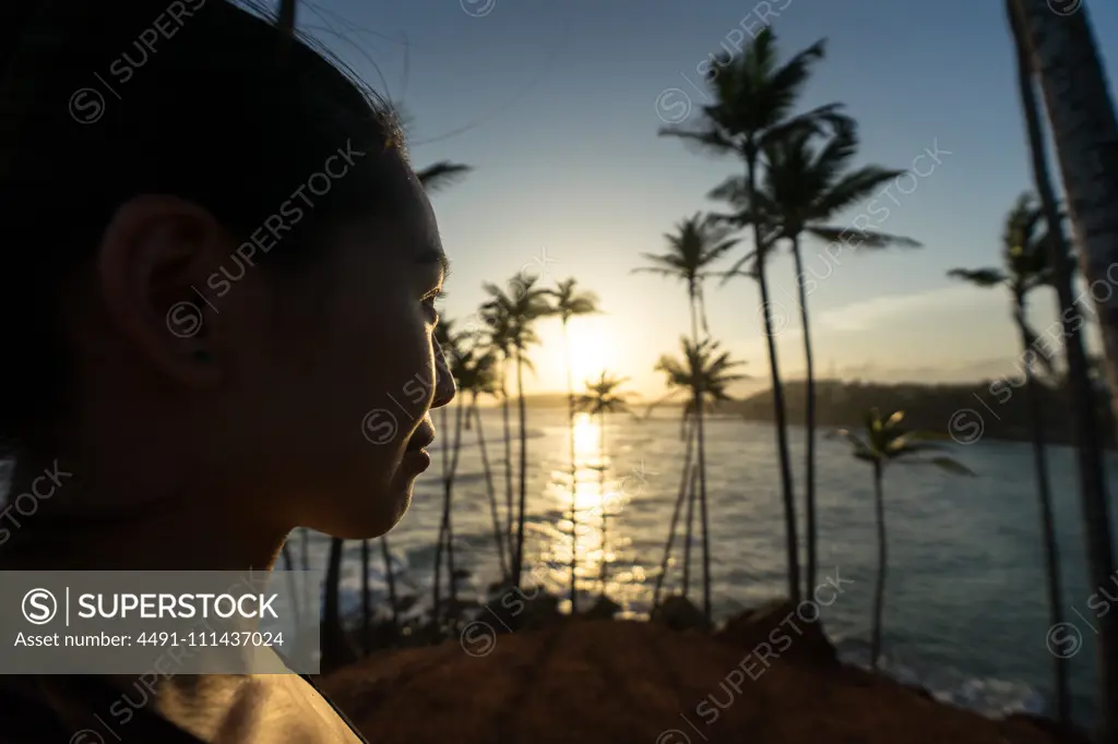 Tranquil female traveler among palms at seashore