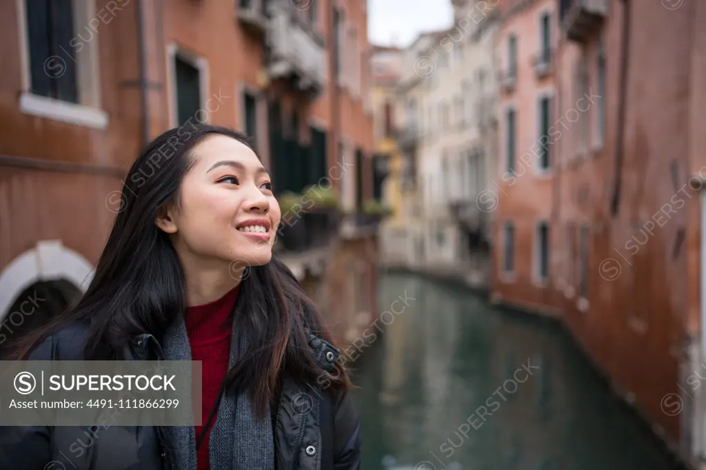 Satisfied Asian resting woman exploring old city with waterways