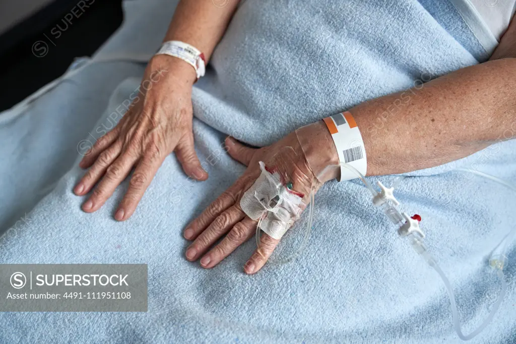 Crop elderly patient receiving medicine through cannula