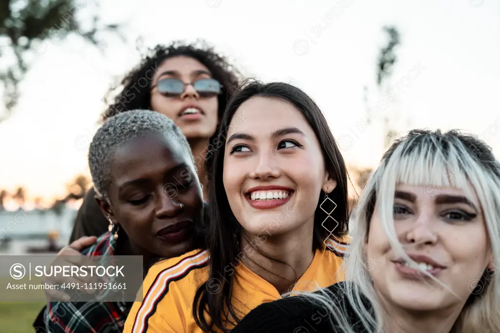 Diverse group of smiling women hugging together on lawn