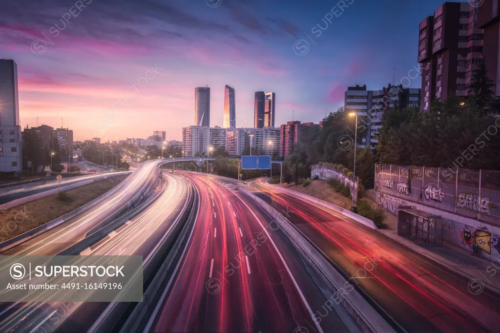 From above colorful car lights along large asphalt road in metropolis against wonderful skyline under vibrant cloudy sky at dusk in Madrid