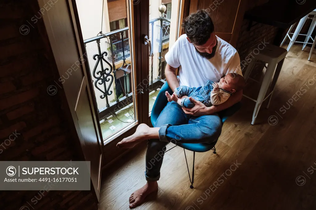 Bearded father with baby sitting near window