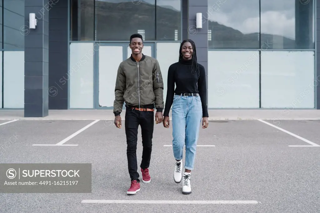 Happy black couple walking outside modern building