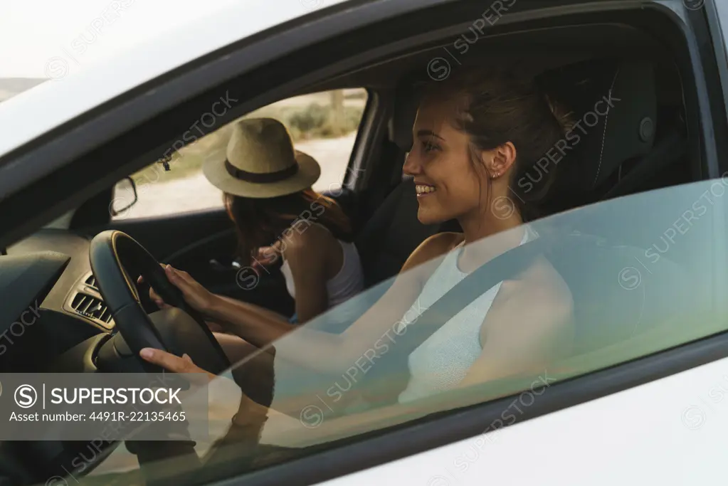 Side view of pretty young women riding a car in nature together.