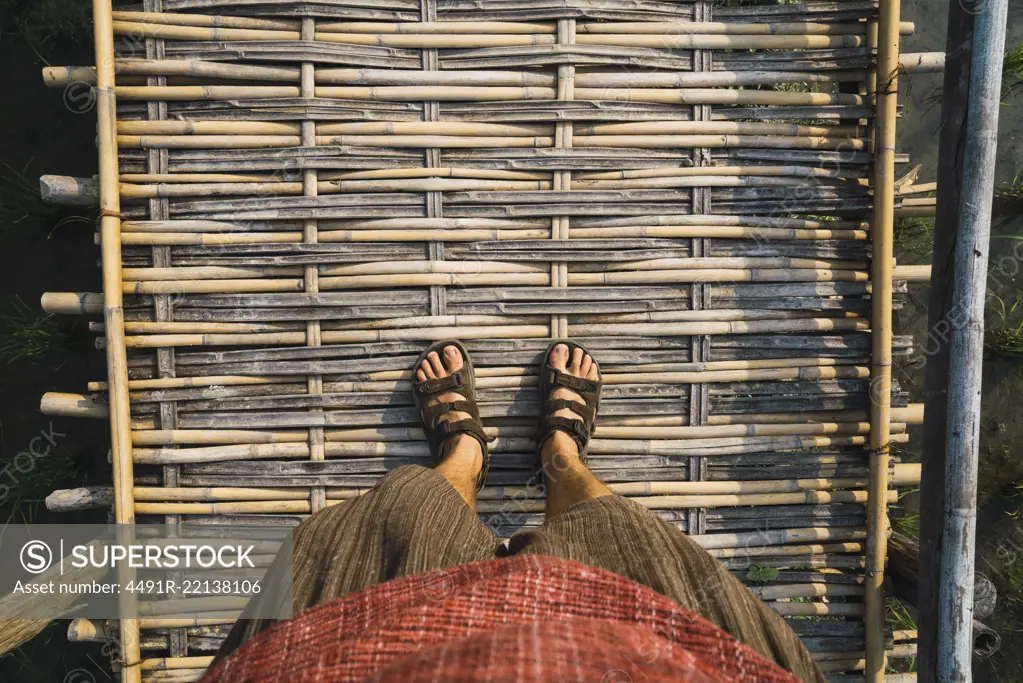 From above legs of unrecognizable tourist standing on straw path.