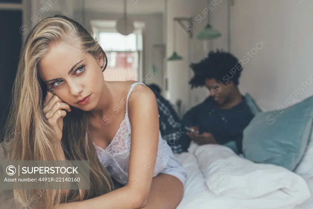 Young beautiful interracial couple in bed stressed with infidelity problems 