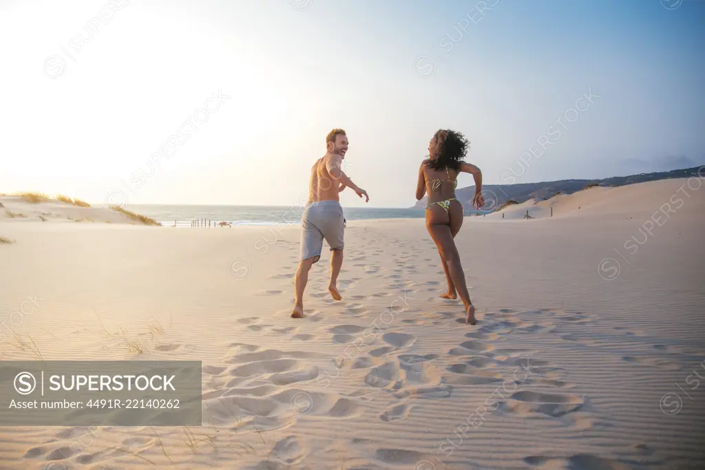 Happy couple running on tropical romantic beach