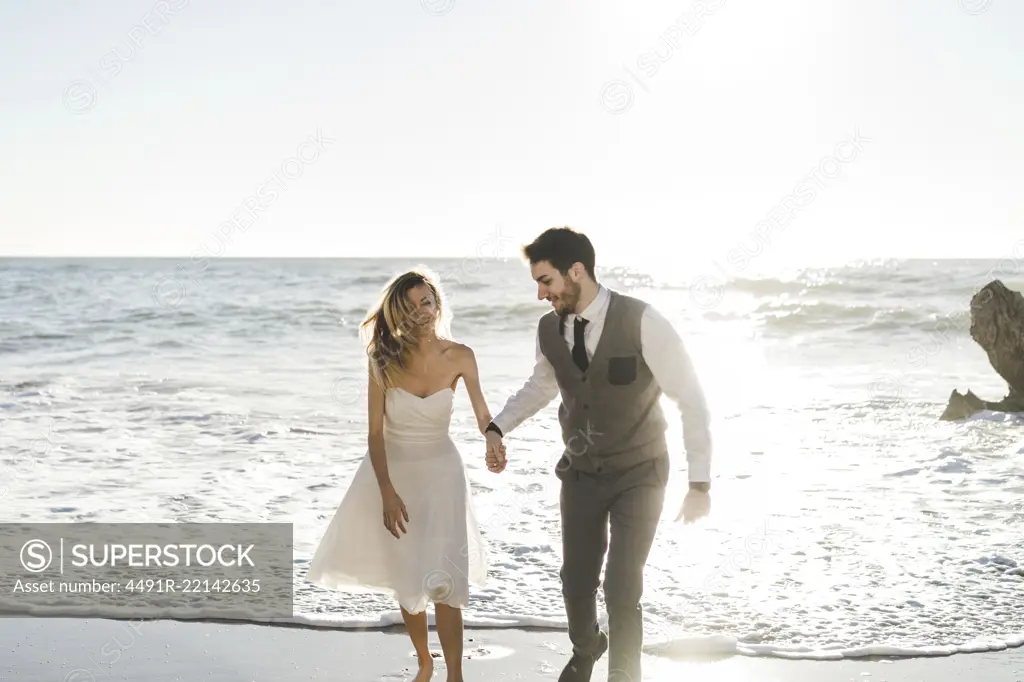 Beautiful bridal couple running on shore