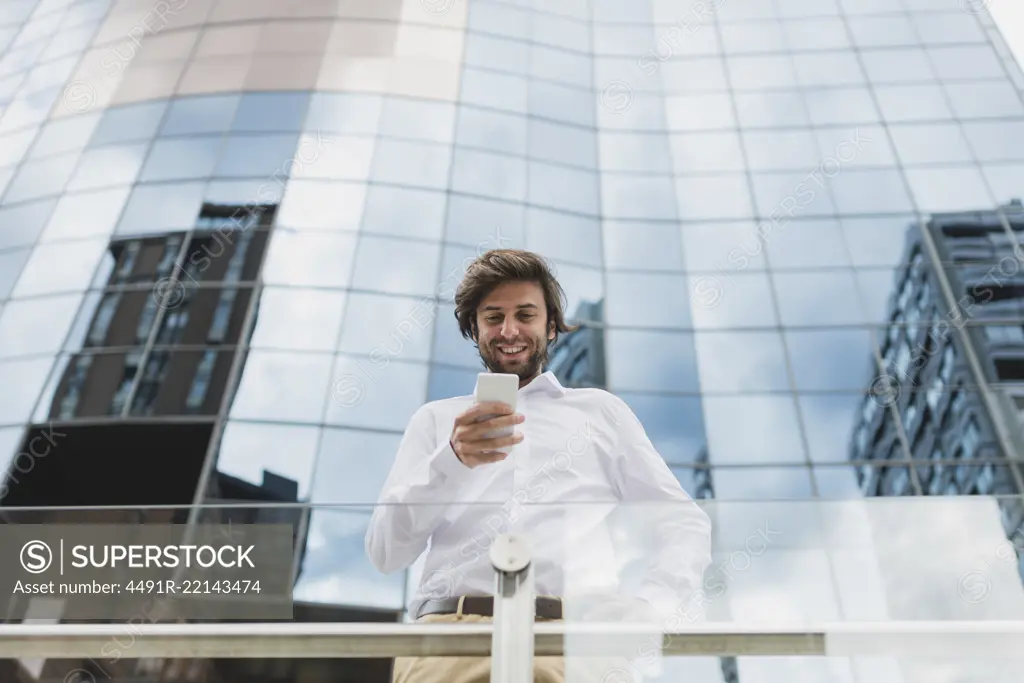 Portrait of confident businessman in white shirt using phone