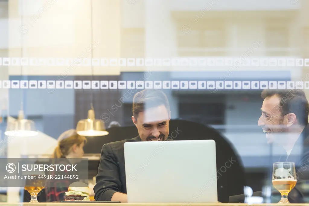 Businessmen at laptop in cafe