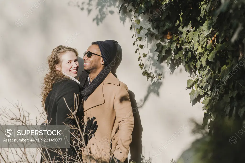 Cheerful multiethnic couple at wall