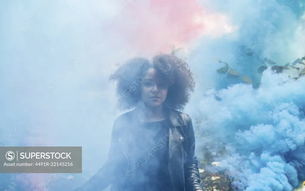 Young woman with colored smoke bombs