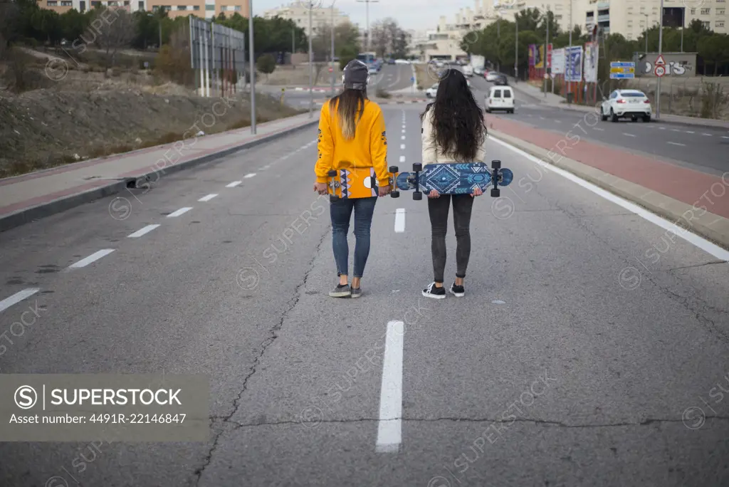 Two girls who play in the street with longboard