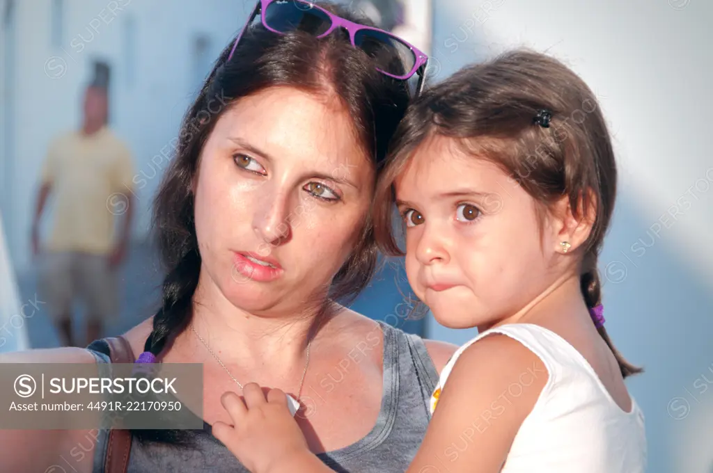 Mother and daughter hugging bathed in soft sunlight walking through the village streets 