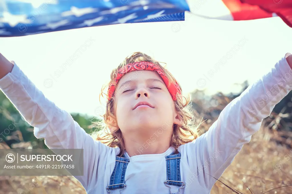 Boy in nature holding an American flag