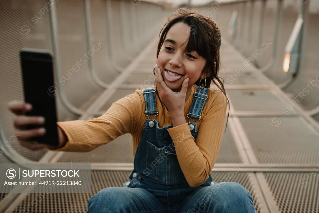 Funny girl taking selfie on smartphone on walkway