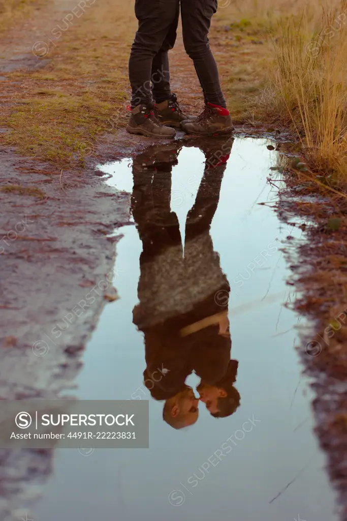 Water slop with reflection of homosexual couple embracing and kissing on road