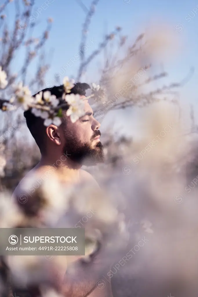 Shirtless man meditating in spring garden