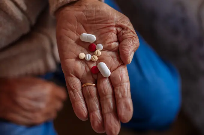 Detail of pills on the hand of an old man