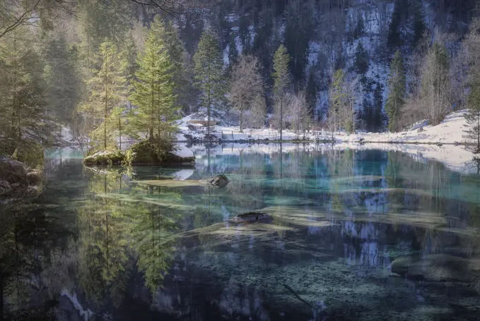 Landscape of peaceful azure lake with snowy shore in mountains of Switzerland