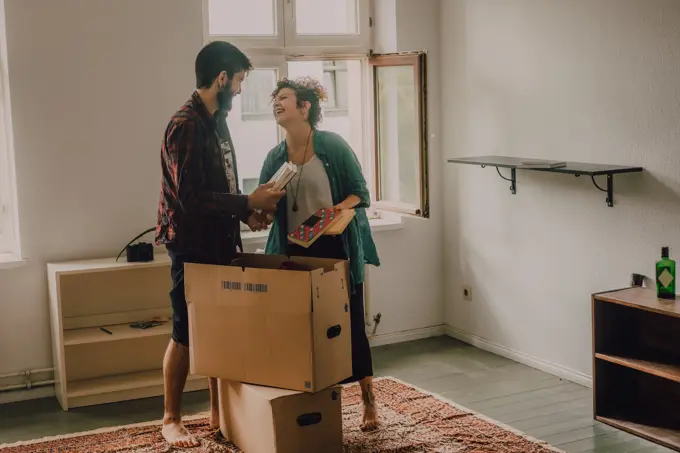 Hipster couple unpacking together boxes while standing barefoot in light room