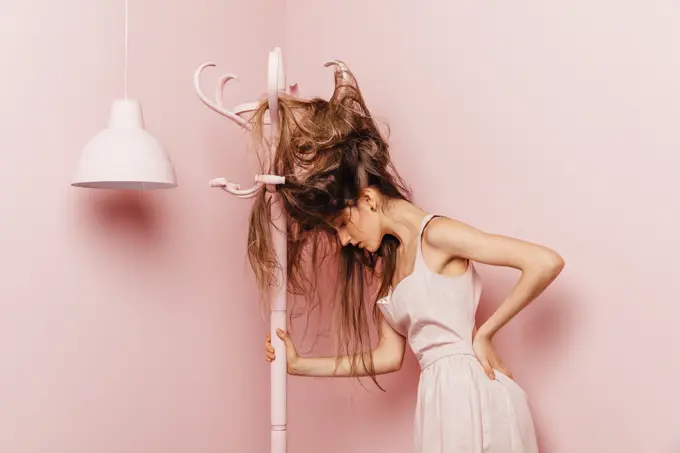 Front view of a teenage girl with tangled hairs on pink background