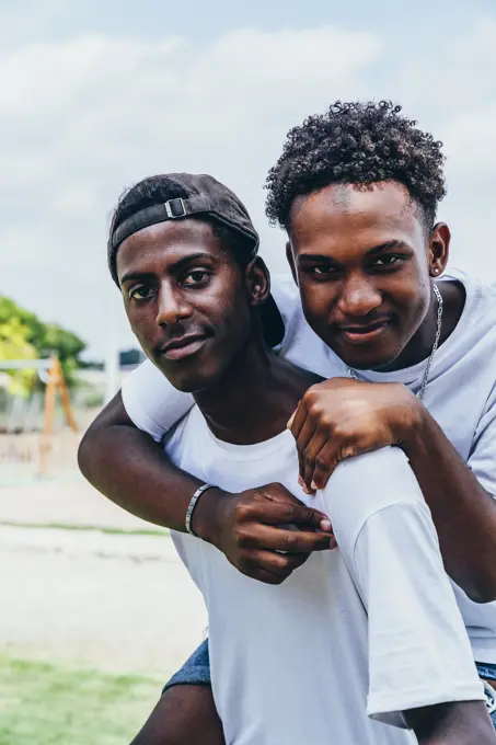 Cheerful hugging African American young men looking at camera and gesturing