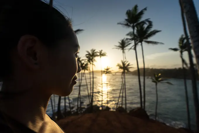 Tranquil female traveler among palms at seashore