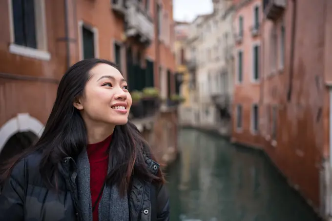 Satisfied Asian resting woman exploring old city with waterways