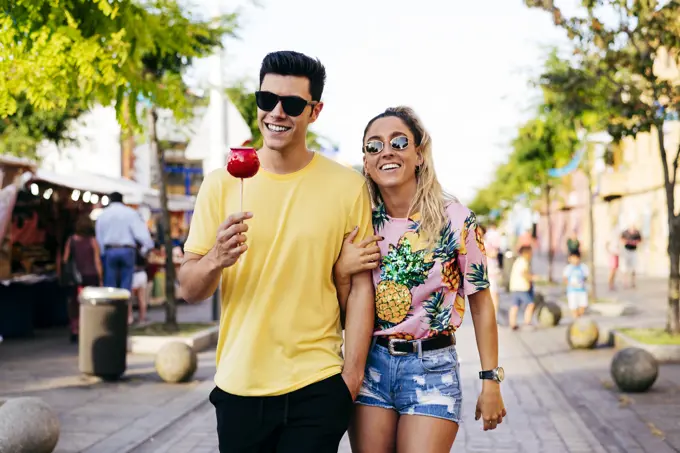 Content couple having fun walking on street in fair