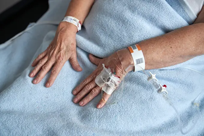 Crop elderly patient receiving medicine through cannula