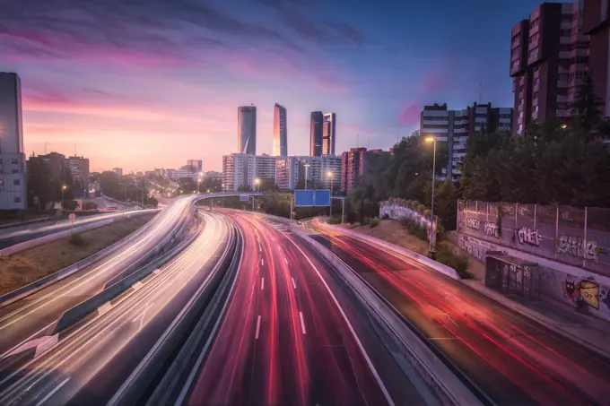 From above colorful car lights along large asphalt road in metropolis against wonderful skyline under vibrant cloudy sky at dusk in Madrid