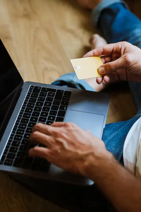 Crop man shopping online on floor