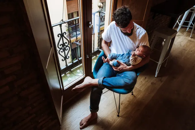 Bearded father with baby sitting near window