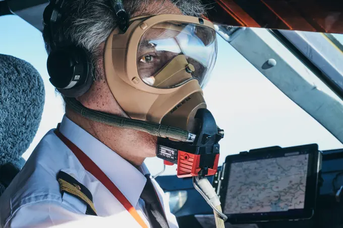 Pilot in mask operating airplane during flight