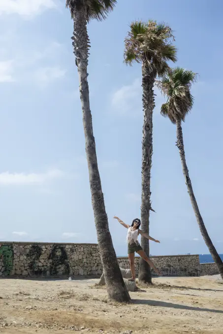 Young pretty hispanic woman on dancing between palm trees