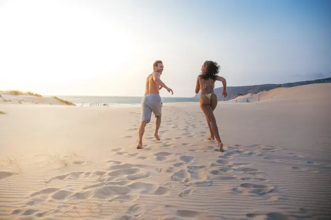 Happy couple running on tropical romantic beach