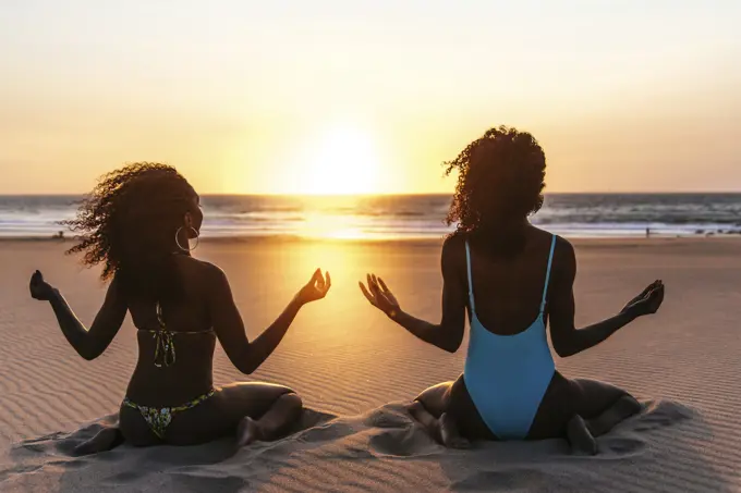 Content models on tropical beach in sunset