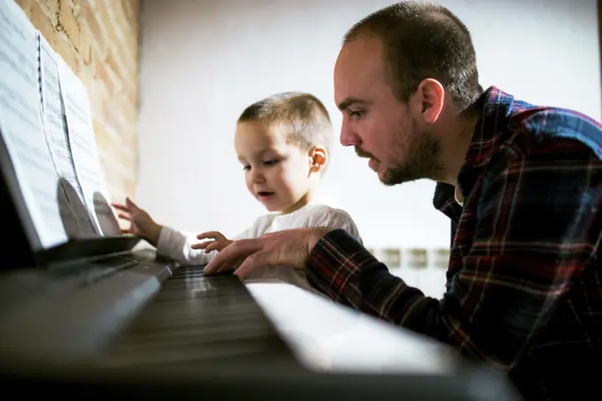 Boy playing piano with parent
