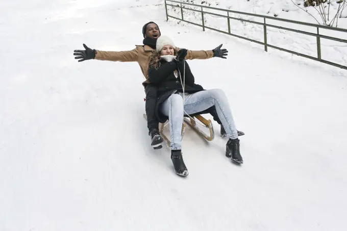 Couple riding sledge on snowy hill