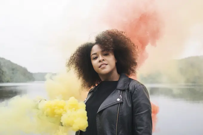 Young woman with colored smoke bombs