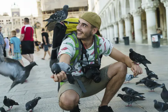 Tourist feeding pigeons on square