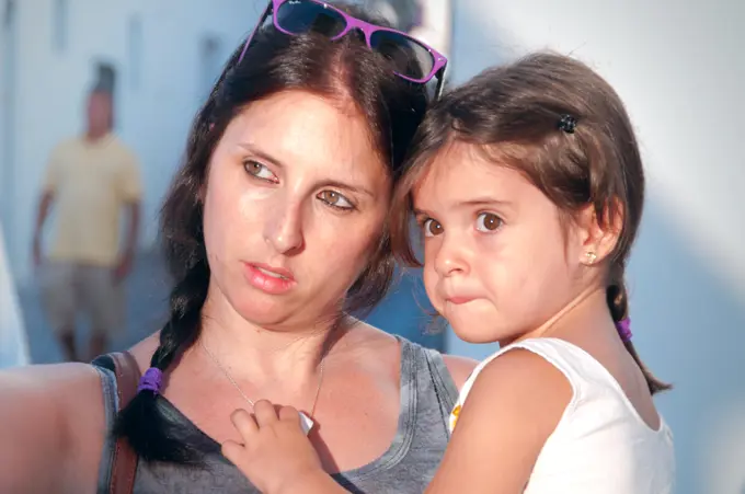 Mother and daughter hugging bathed in soft sunlight walking through the village streets 